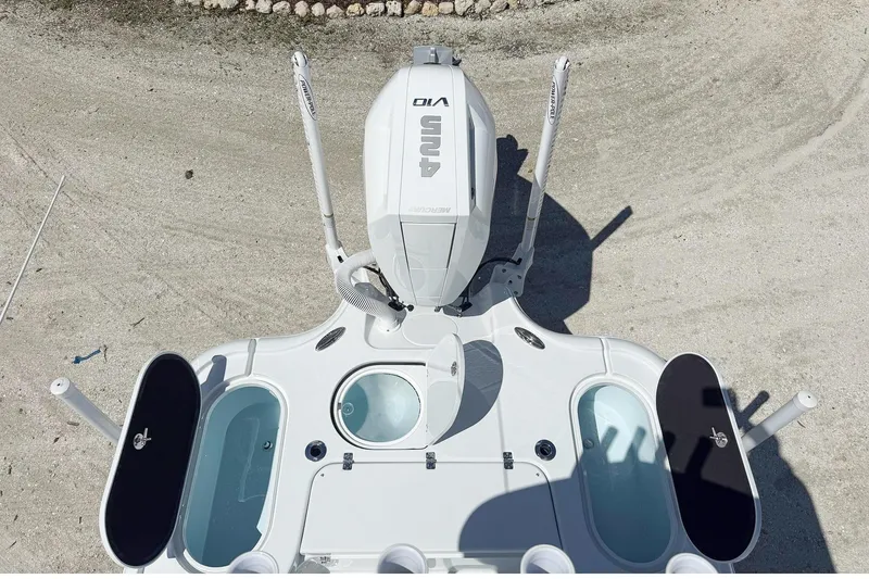 Slide: The Image of 2026 Yellowfin 24 Bay CE boat with open storage compartment, surrounded by palm trees. - 9