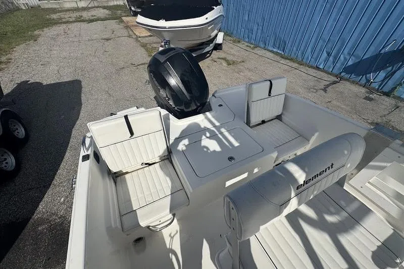Slide: The Image of 2018 Bayliner Element F21 boat interior with seating and motor, parked outdoors. - 10