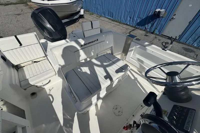 Slide: The Image of 2018 Bayliner Element F21 boat interior with white seating and steering wheel. - 6