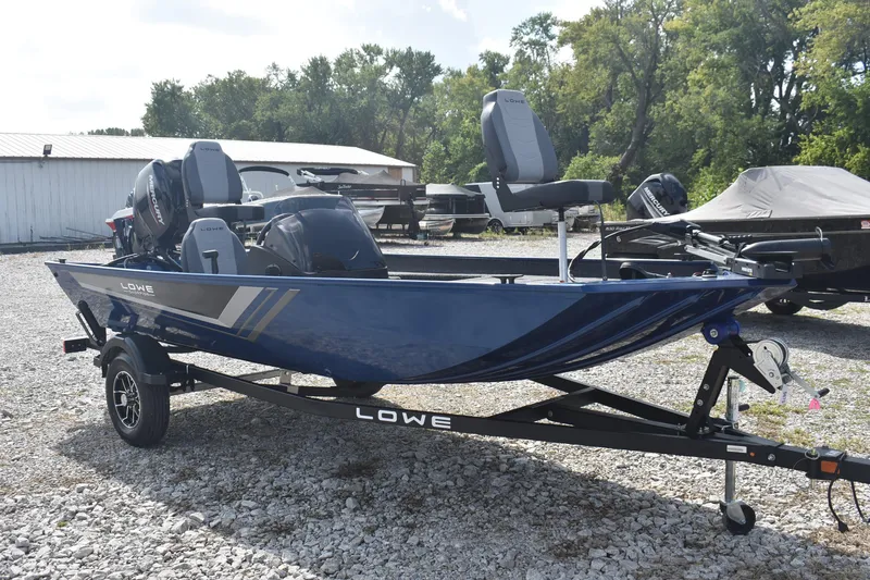 Slide: The Image of 2026 Lowe Skorpion 17 boat on trailer, parked on gravel lot. - 2