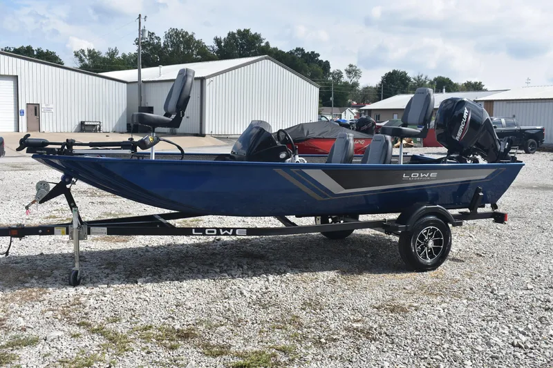 Slide: The Image of 2026 Lowe Skorpion 17 boat with outboard motor, parked on gravel lot. - 5