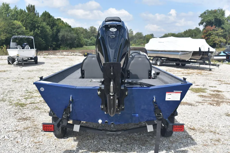 Slide: The Image of 2026 Lowe Skorpion 17 boat with Mercury outboard motor, parked on gravel with trees in background. - 6