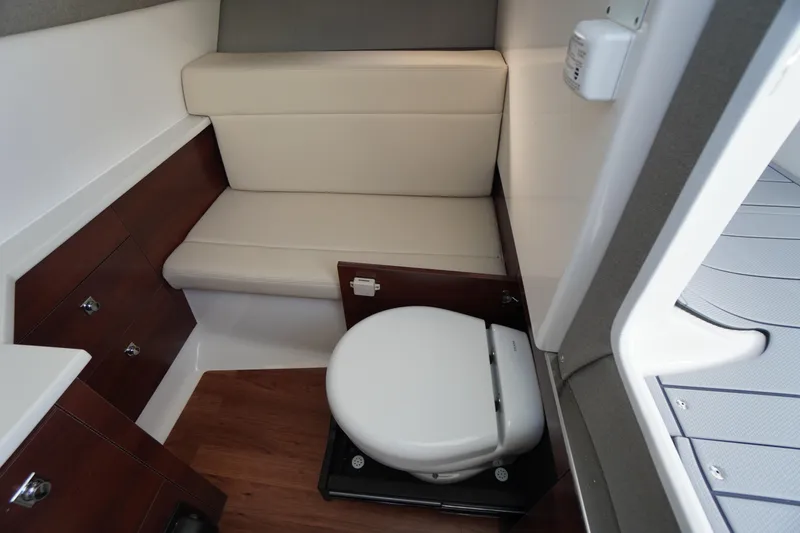 Slide: The Image of 2026 Chaparral 280 OSX boat interior with compact bathroom and seating area. - 24
