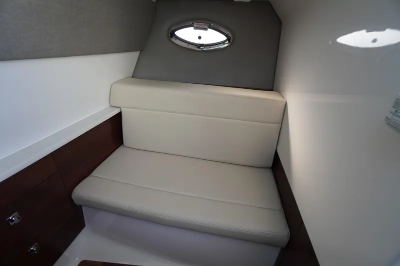 Slide: The Image of 2026 Chaparral 280 OSX cabin interior with cushioned seating and porthole window. - 26
