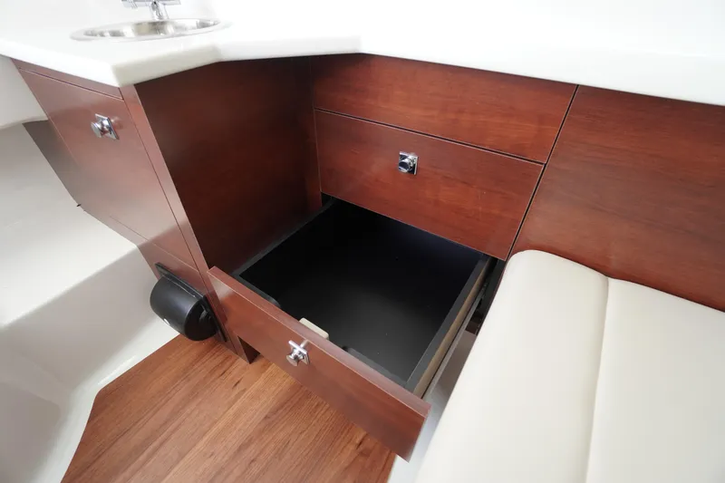 Slide: The Image of 2026 Chaparral 280 OSX interior with open wooden storage cabinet and sink. - 28