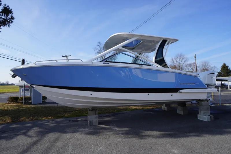 Slide: The Image of 2026 Chaparral 280 OSX boat in blue, displayed outdoors on supports. - 70