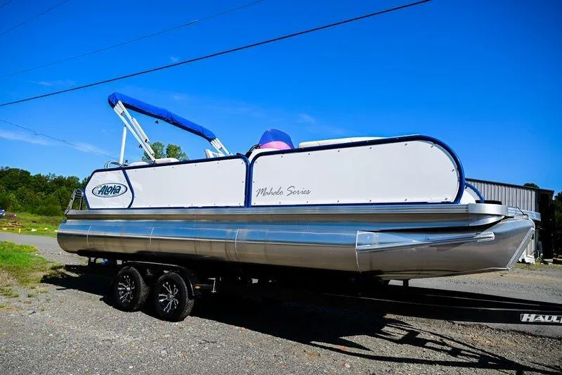 Slide: The Image of 2023 Aloha Pontoon boat on trailer under clear blue sky. - 3