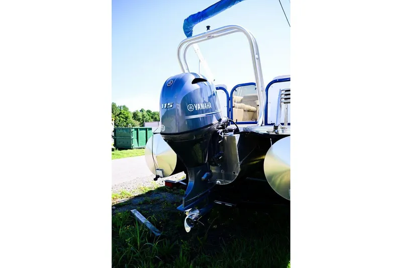Slide: The Image of 2023 Aloha Pontoon with Yamaha 115 outboard motor, parked on grass. - 9