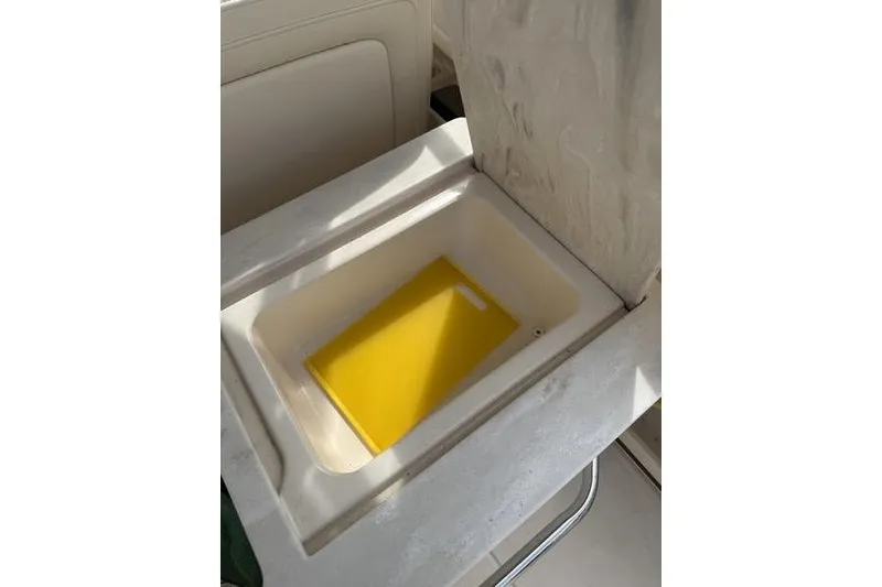 Slide: The Image of 2019 Grady-White Freedom 285 boat interior with built-in storage compartment and yellow cutting board. - 10