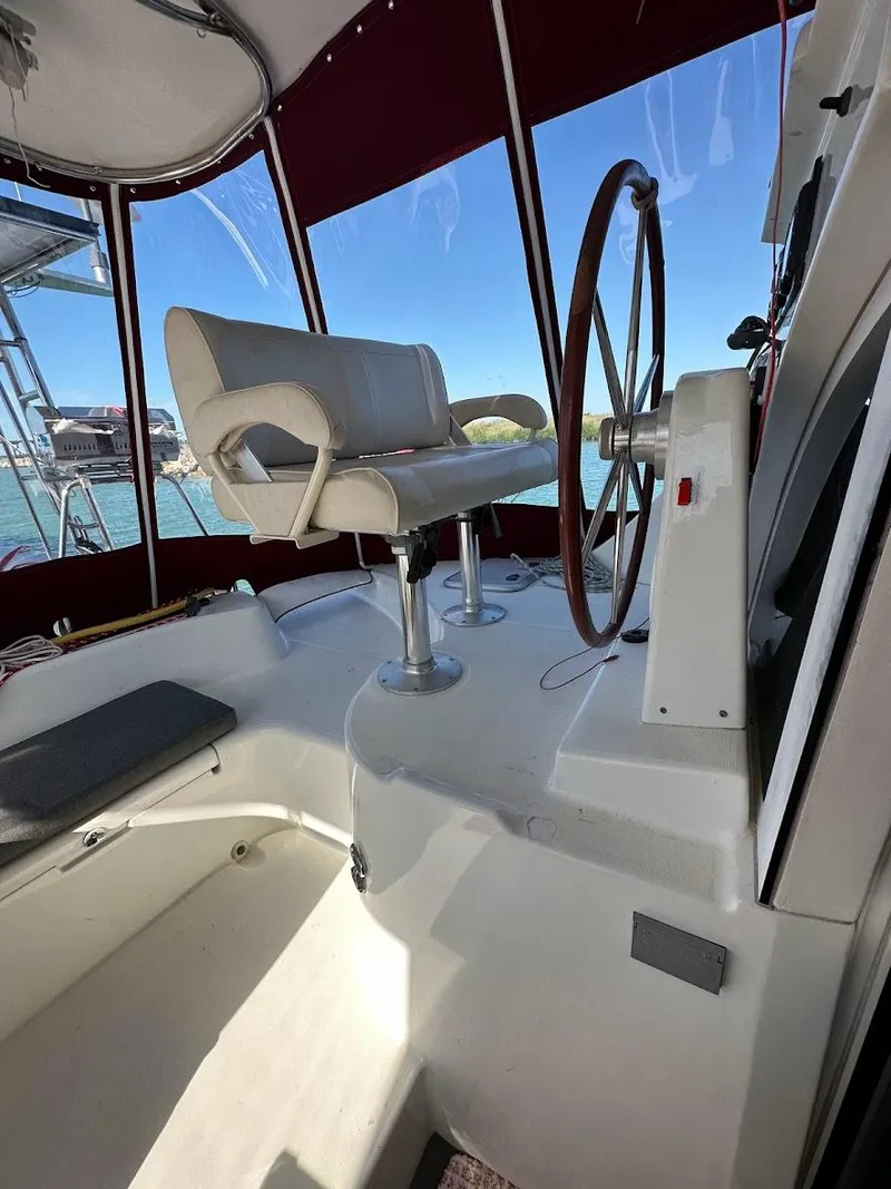 Slide: The Image of 2004 Lagoon 380 yacht cockpit with steering wheel and seating, featuring a scenic water view. - 22