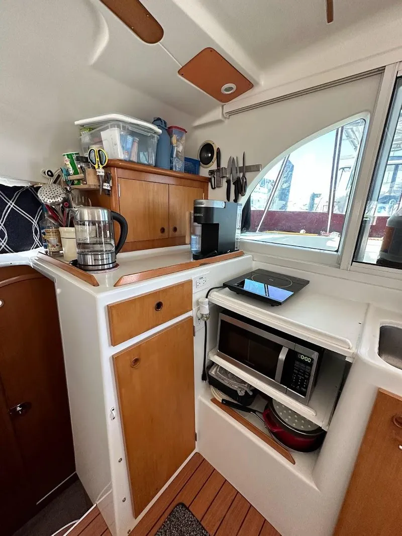 Slide: The Image of Compact kitchen in a 2004 Lagoon 380 catamaran with wooden cabinets and modern appliances. - 7
