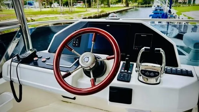 Slide: The Image of Helm of 2022 Greenline 48 Flybridge with Hardtop, featuring modern controls and red steering wheel. - 23