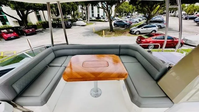 Slide: The Image of Flybridge seating area on 2022 Greenline 48 with Hardtop, featuring a wooden table and gray cushions. - 29