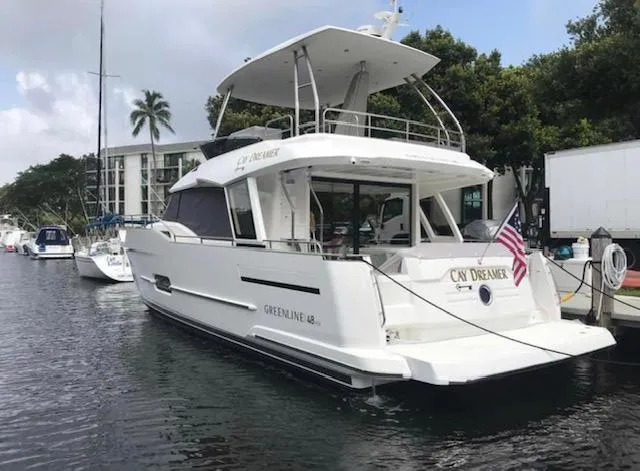 Slide: The Image of 2022 Greenline 48 Flybridge yacht with hardtop docked, featuring sleek design and American flag. - 38