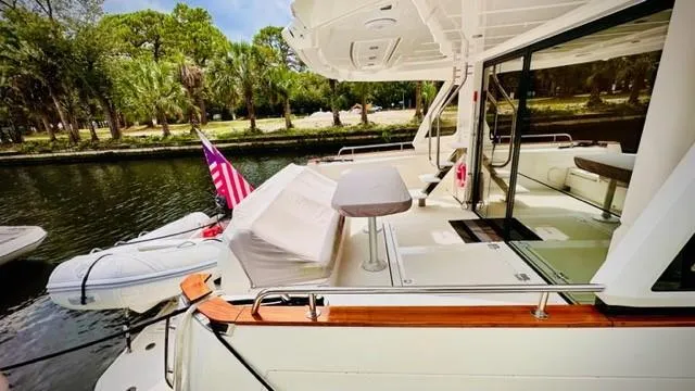 Slide: The Image of 2022 Greenline 48 Flybridge yacht with hardtop, docked near lush greenery. - 4