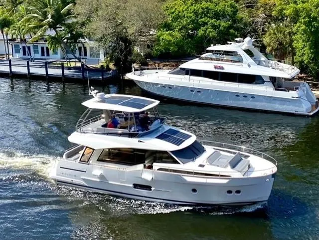 Slide: The Image of 2022 Greenline 48 Flybridge yacht with hardtop, docked by lush greenery. - 40