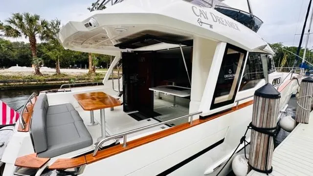 Slide: The Image of 2022 Greenline 48 Flybridge yacht with hardtop, docked, featuring outdoor seating and dining area. - 8