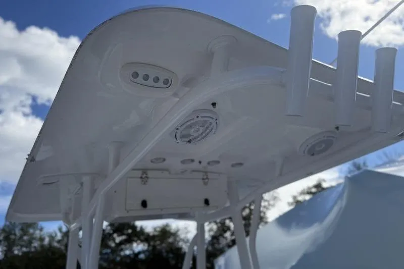 Slide: The Image of 2024 Sea Hunt Ultra 229 boat canopy with rod holders and speakers under a blue sky. - 11