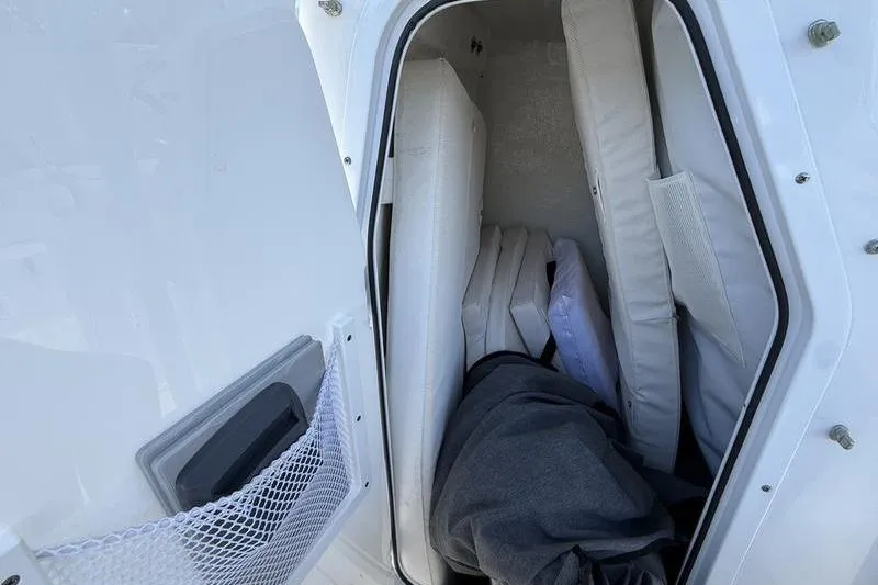 Slide: The Image of 2024 Sea Hunt Ultra 229 storage compartment with cushions and gear. - 9
