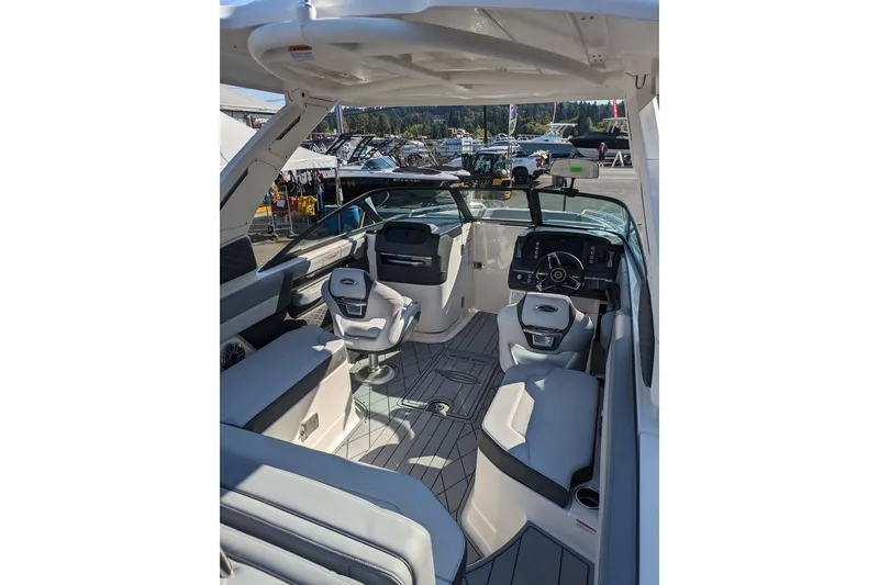 Slide: The Image of 2026 Chaparral 6 GTS boat interior with modern seating and dashboard at a marina. - 11