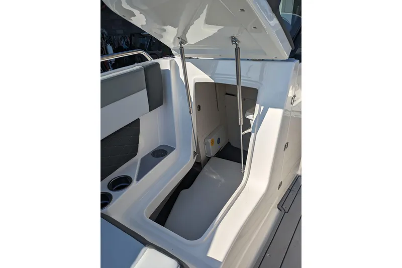 Slide: The Image of 2026 Chaparral 6 GTS boat storage compartment with open hatch and cup holders. - 25