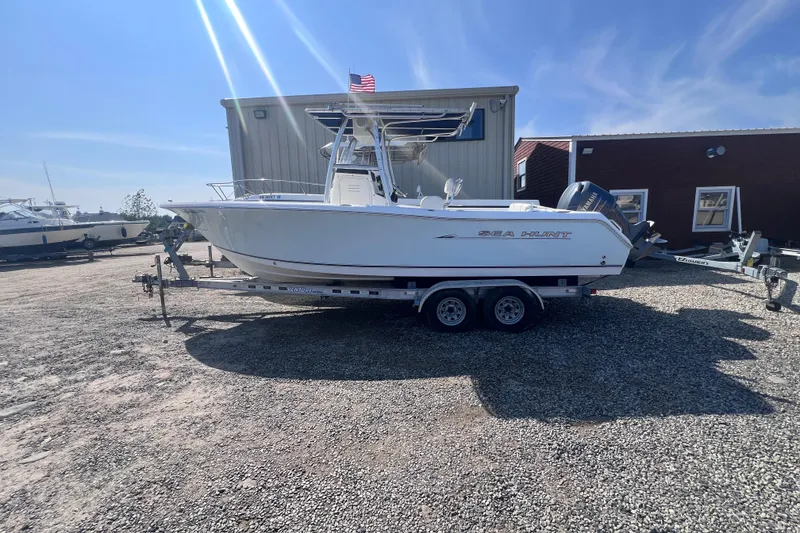 Slide: The Image of 2007 Sea Hunt Triton 240 boat on trailer, parked outdoors under clear sky. - 0