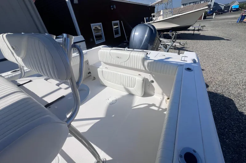 Slide: The Image of 2007 Sea Hunt Triton 240 boat interior with white seating and motor, parked on gravel. - 14