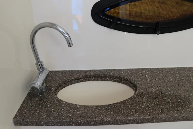 Slide: The Image of 2019 Hurricane SunDeck 2486 OB boat sink with chrome faucet and oval window. - 45