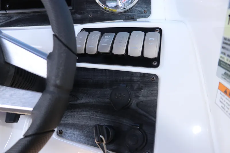 Slide: The Image of Dashboard controls of a 2019 Hurricane SunDeck 2486 OB boat, featuring switches and steering wheel. - 51