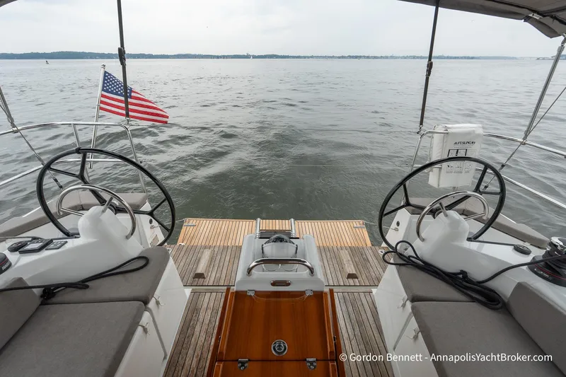 Slide: The Image of 2022 Jeanneau Sun Odyssey 410 yacht cockpit with dual steering wheels and American flag. - 10