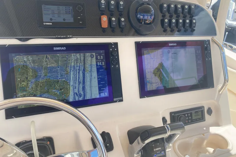 Slide: The Image of 2018 Grady-White Canyon 306 dashboard with Simrad navigation displays and Yamaha controls. - 8