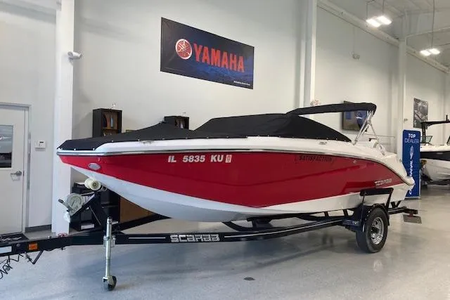 Slide: The Image of 2015 Scarab 215 boat in showroom, red and white, on trailer, Yamaha sign above. - 3
