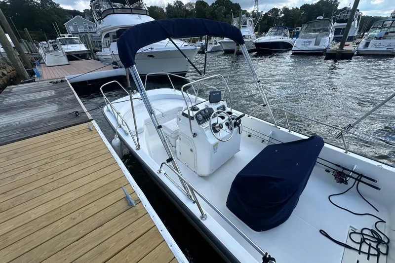 Slide: The Image of 2016 Boston Whaler 170 Montauk docked at marina, featuring blue canopy and console. - 2