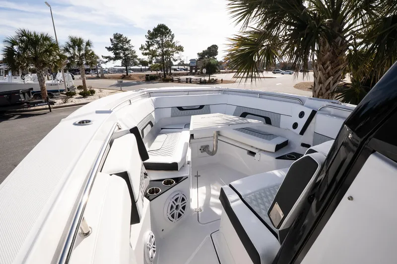 Slide: The Image of 2026 Blackfin 302 CC boat interior with seating and table, surrounded by palm trees. - 20