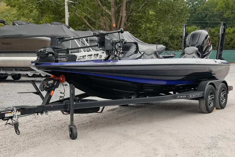 Slide: The Image of 2024 Skeeter ZXR20 boat on trailer, parked outdoors with trees in background. - 4