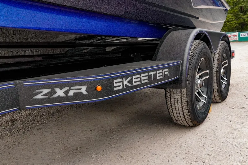 Slide: The Image of 2024 Skeeter ZXR20 boat trailer with dual wheels on gravel surface. - 9