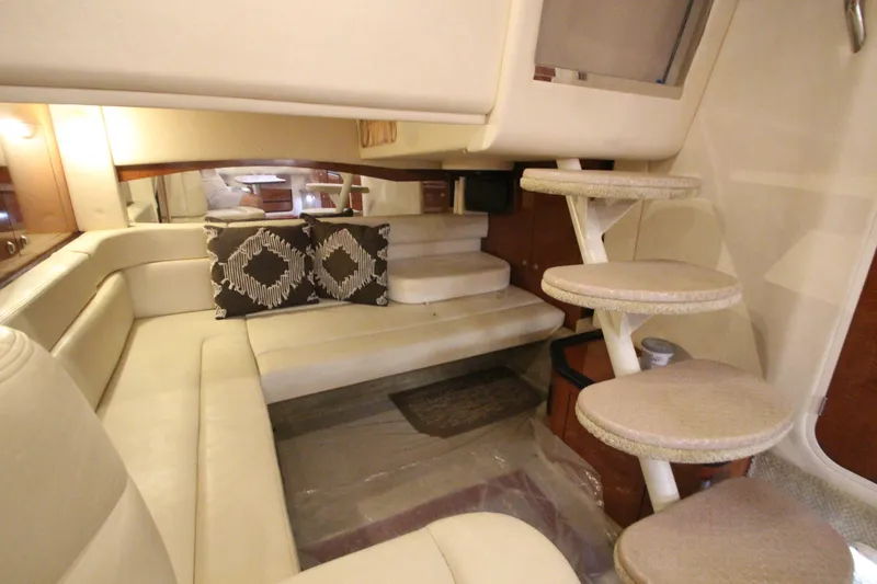 Slide: The Image of 2005 Sea Ray 340 Sundancer interior with beige seating, decorative pillows, and spiral stairs. - 14