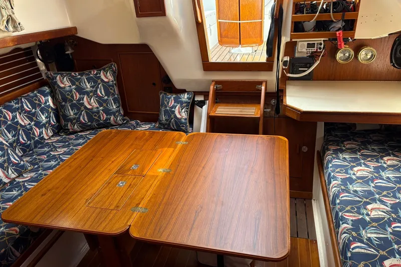 Slide: The Image of 1988 Nonsuch 30 Ultra yacht interior with wooden table and nautical-themed cushions. - 10