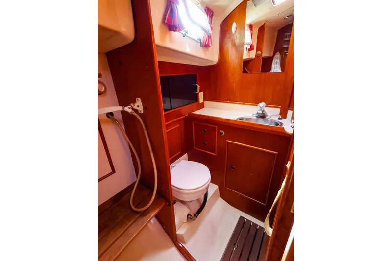 Slide: The Image of 1988 Nonsuch 30 Ultra yacht bathroom with wooden cabinetry, sink, and toilet. - 21
