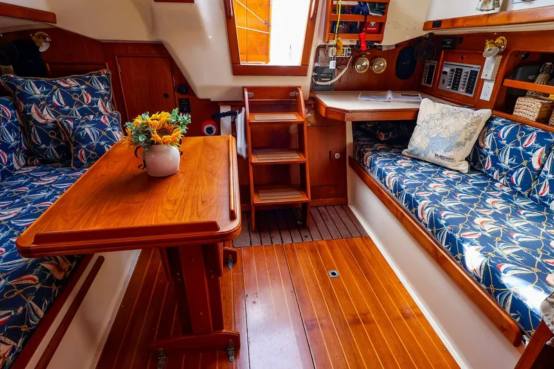 Slide: The Image of Cozy 1988 Nonsuch 30 Ultra yacht interior with floral cushions and wooden table. - 6