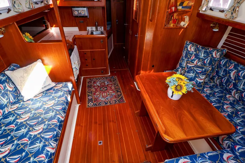 Slide: The Image of Cozy 1988 Nonsuch 30 Ultra yacht interior with nautical-themed cushions and wooden furnishings. - 9