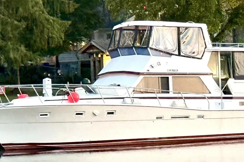 The Image of 1987 Viking 44 Motor Yacht docked, surrounded by lush greenery. - 1