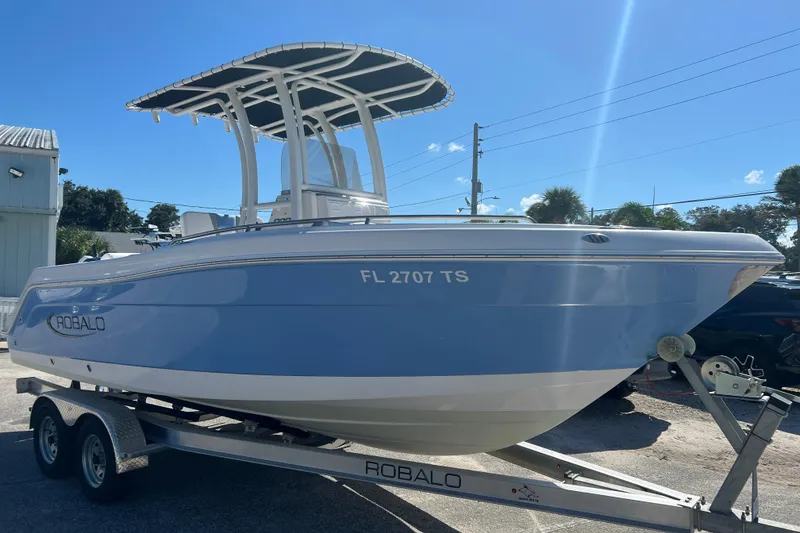 Slide: The Image of 2024 Robalo R222 Center Console boat on trailer under clear blue sky. - 6