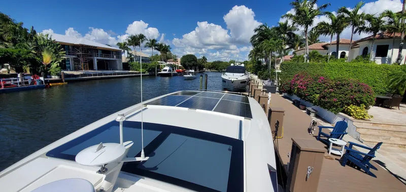 Slide: The Image of Greenline 40 yacht docked in a sunny, tropical canal with palm trees and luxury homes. - 10