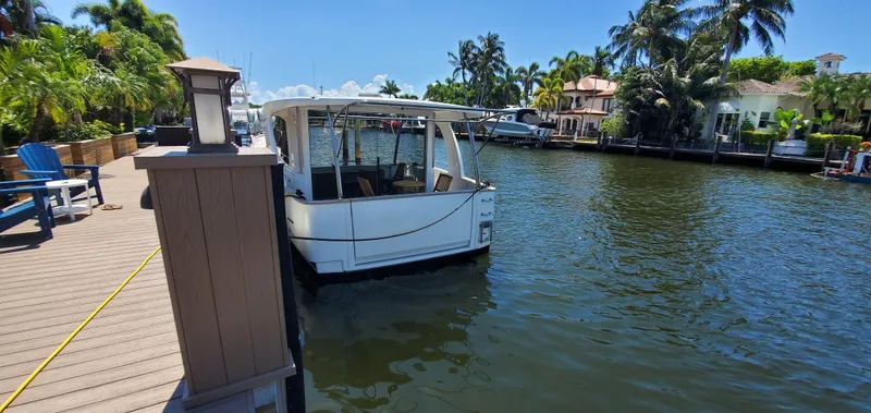 Slide: The Image of 2023 Greenline 40 boat docked on a sunny waterfront with palm trees and houses. - 13