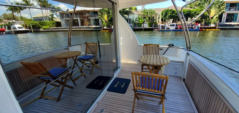 Slide: The Image of Deck of 2023 Greenline 40 yacht with wooden chairs and tables, overlooking a serene waterfront. - 18