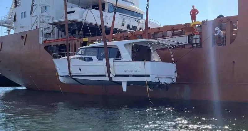 Slide: The Image of 2023 Greenline 40 yacht being lifted by crane onto a cargo ship. - 3