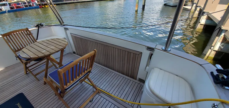 Slide: The Image of 2023 Greenline 40 yacht deck with wooden chairs and table by the water. - 30
