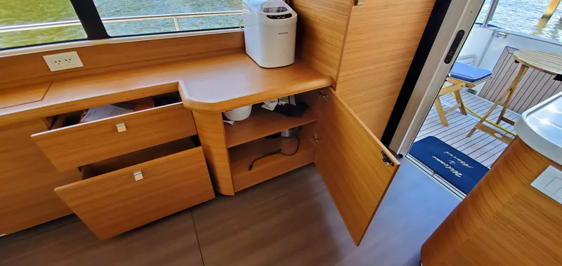 Slide: The Image of Interior of 2023 Greenline 40 yacht with open wooden cabinets and outdoor seating area. - 43