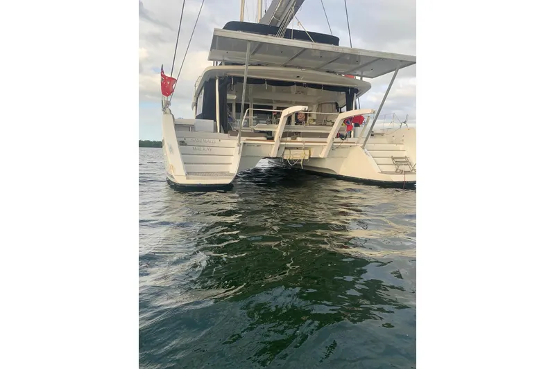 Slide: The Image of 2017 Lagoon 52 F catamaran sailing on blue water near a lush green hillside. - 5